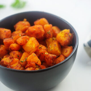 Cooked cubes of butternut squash in a black bowl