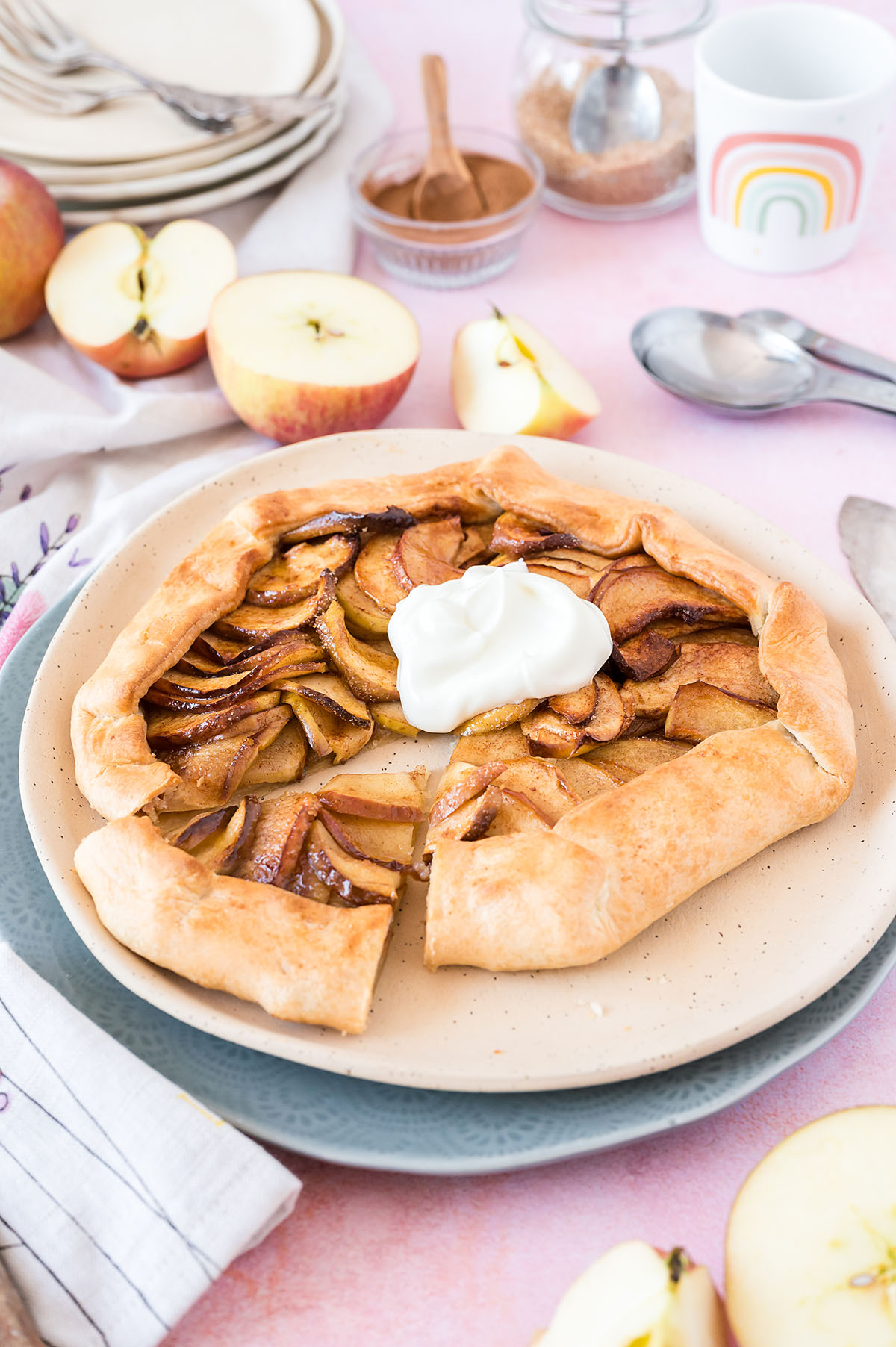 Cooked and cut apple galette on a counter surrounded by ingredients for the recipe.