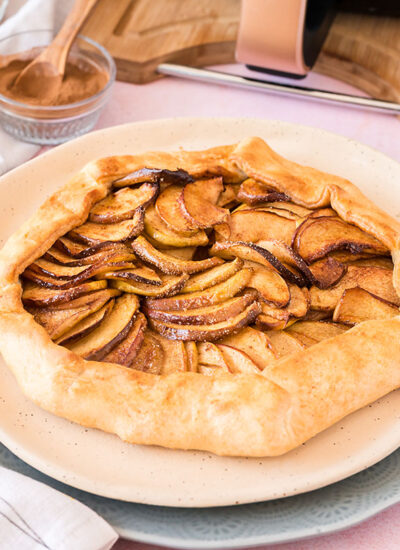 Cooked apple galette next to an kitchen utensils.