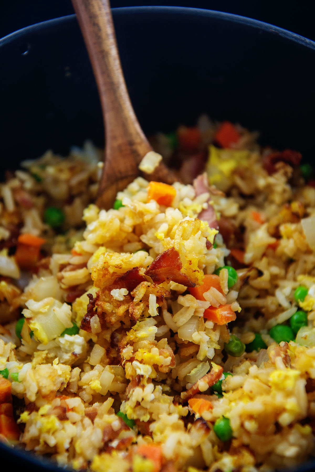 A wooden spoon dipping into fried rice.