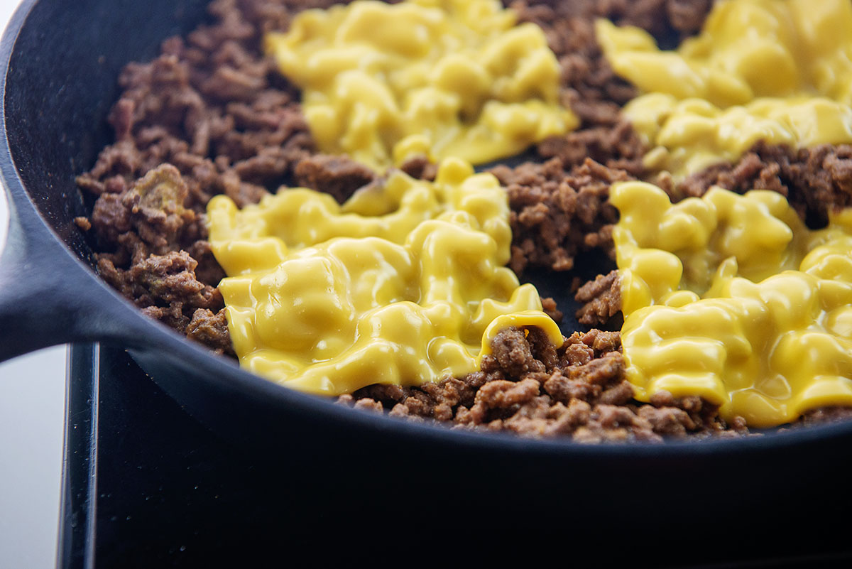 Bround beef and cheese in a skillet.
