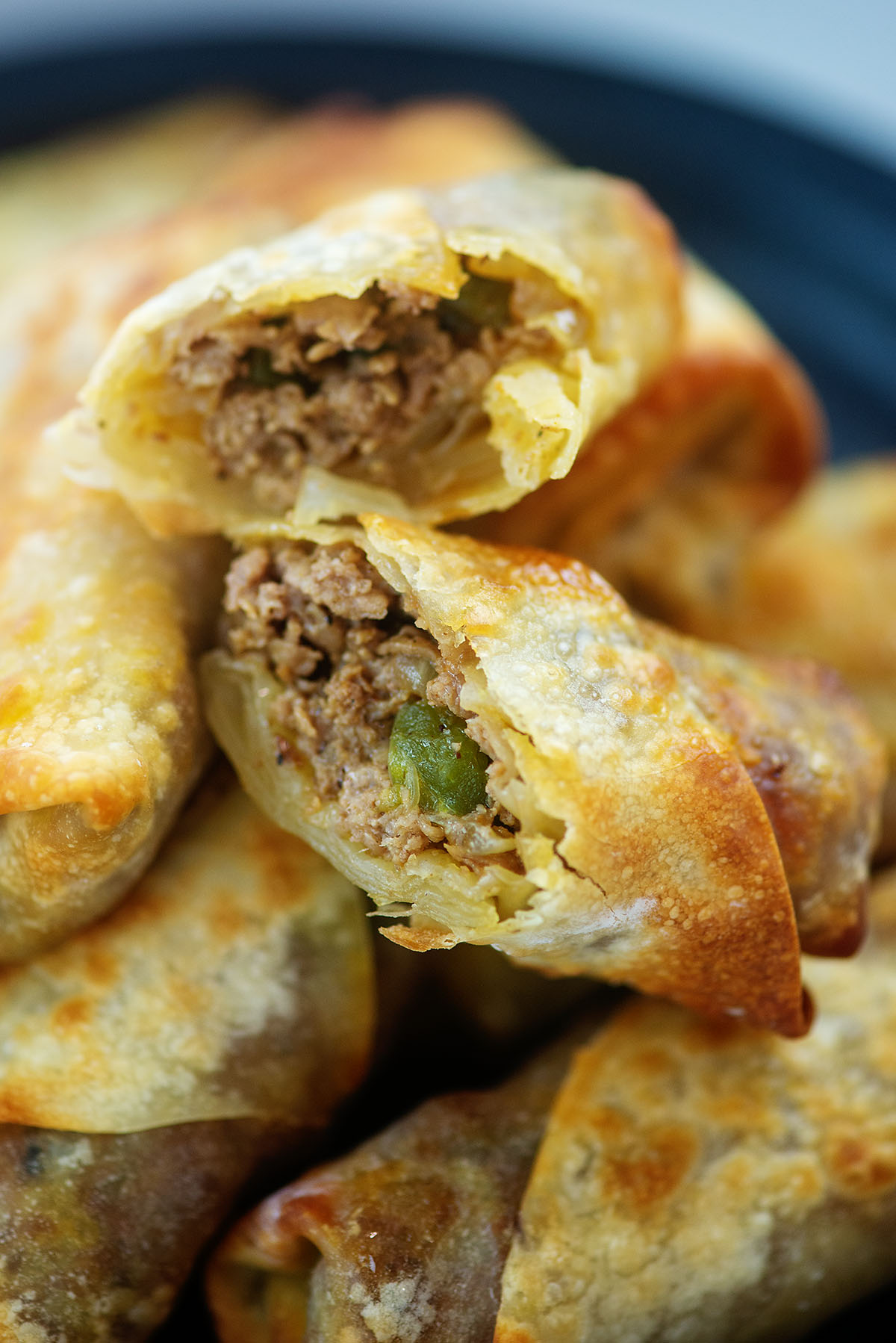 stacked philly cheese steak egg rolls with the one on top spilt open