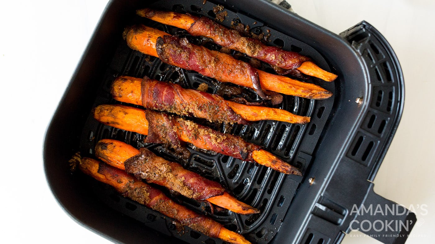 Bacon wrapped carrots in an air fryer basket.