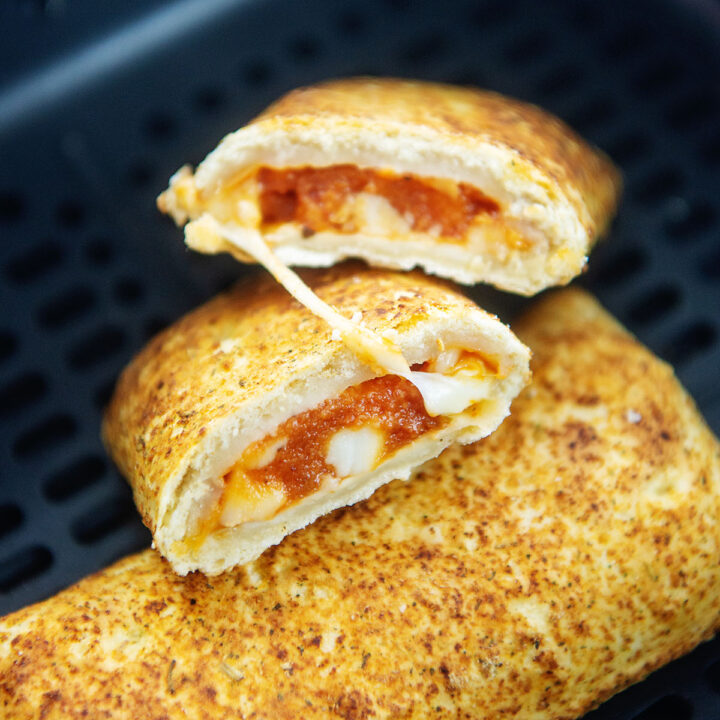 Two hot pockets resting in an air fryer basket.