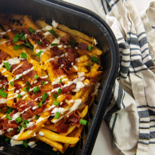 An air fryer basket with loaded fries in it.