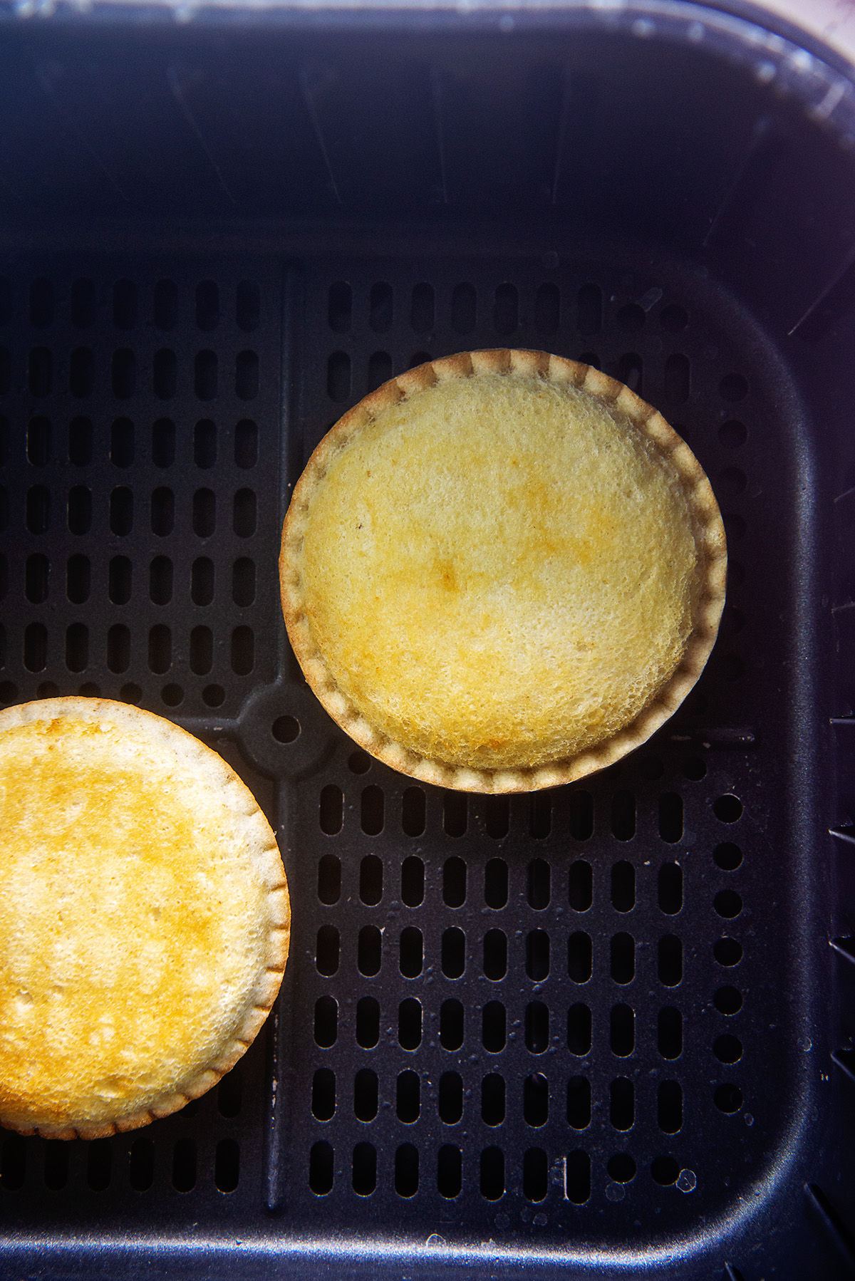 two cooked uncrustables in an air fryer basket.