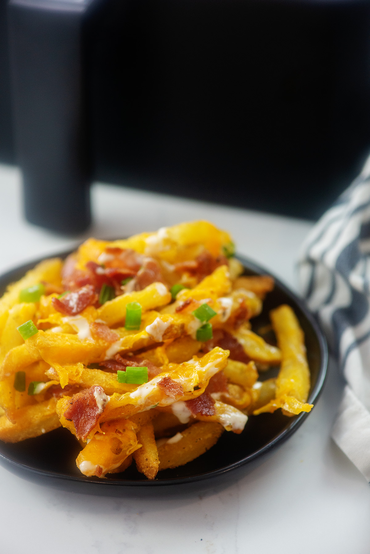 Loaded fries on a small black plate.