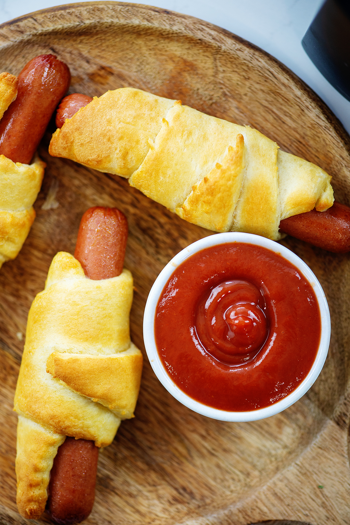 air fried pigs in a blanket on wooden board with ketchup.