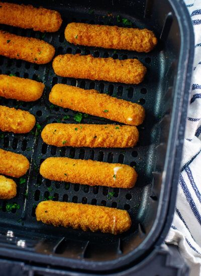 Two rows of cheese sticks in an air fryer basket.