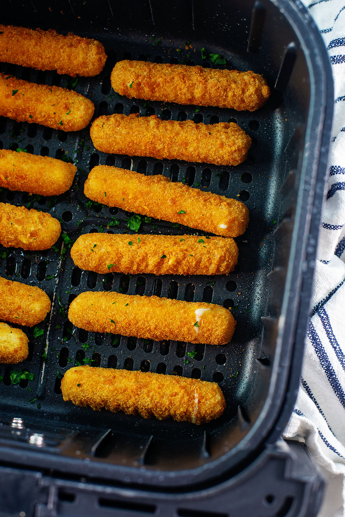 Two rows of cheese sticks in an air fryer basket.