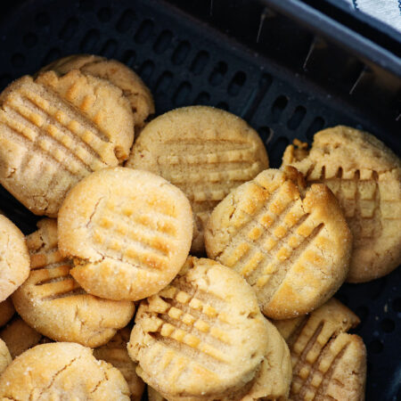 STacked up peanut butter cookies in an air fryer basket.
