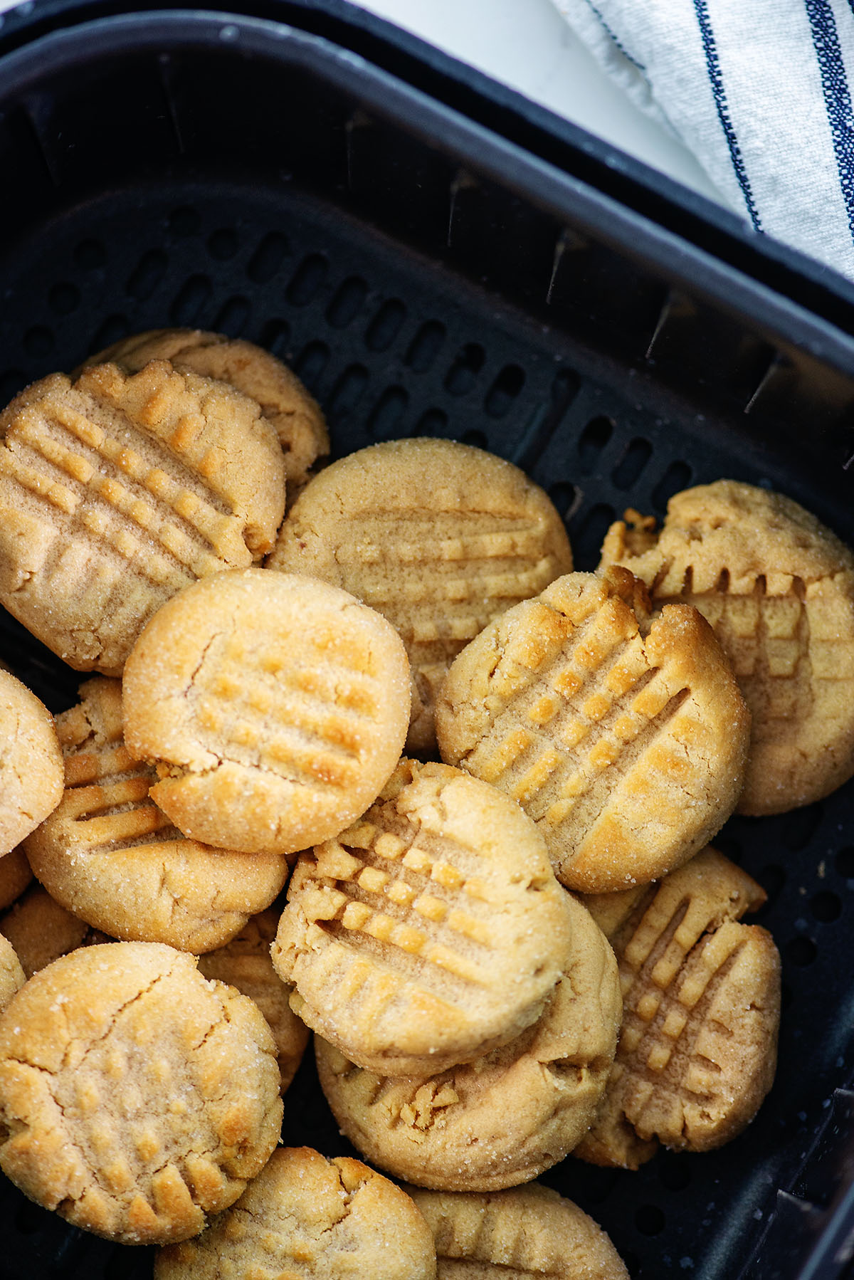 STacked up peanut butter cookies in an air fryer basket.