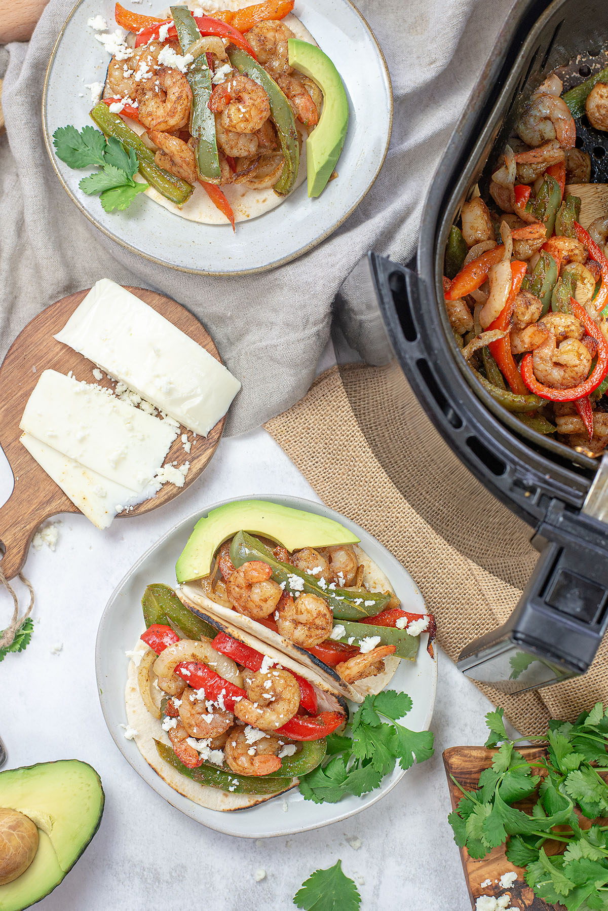 Overhead view of plates of fajitas next to an air fryer.