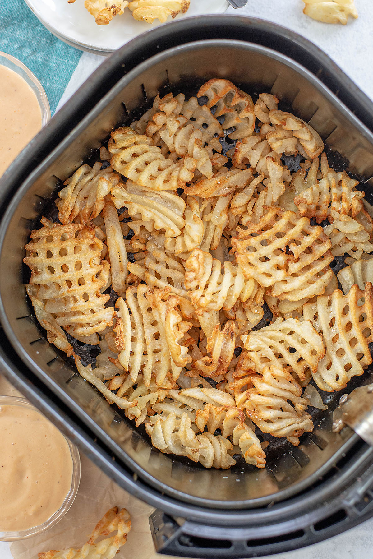 Overhead view of cooked waffle fries in an air fryer basket.