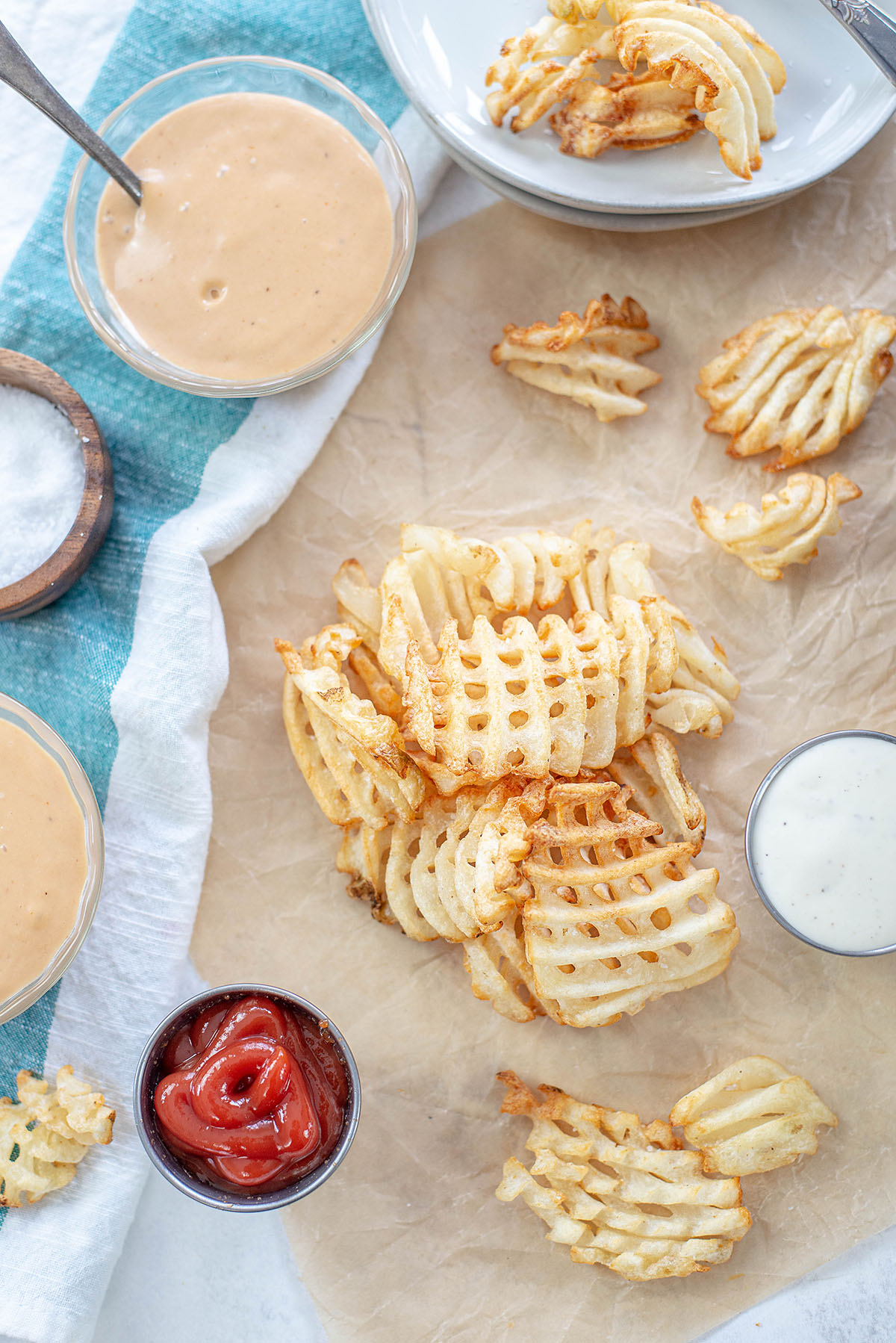 Overhead view of waffle fries surrounded by different dips.