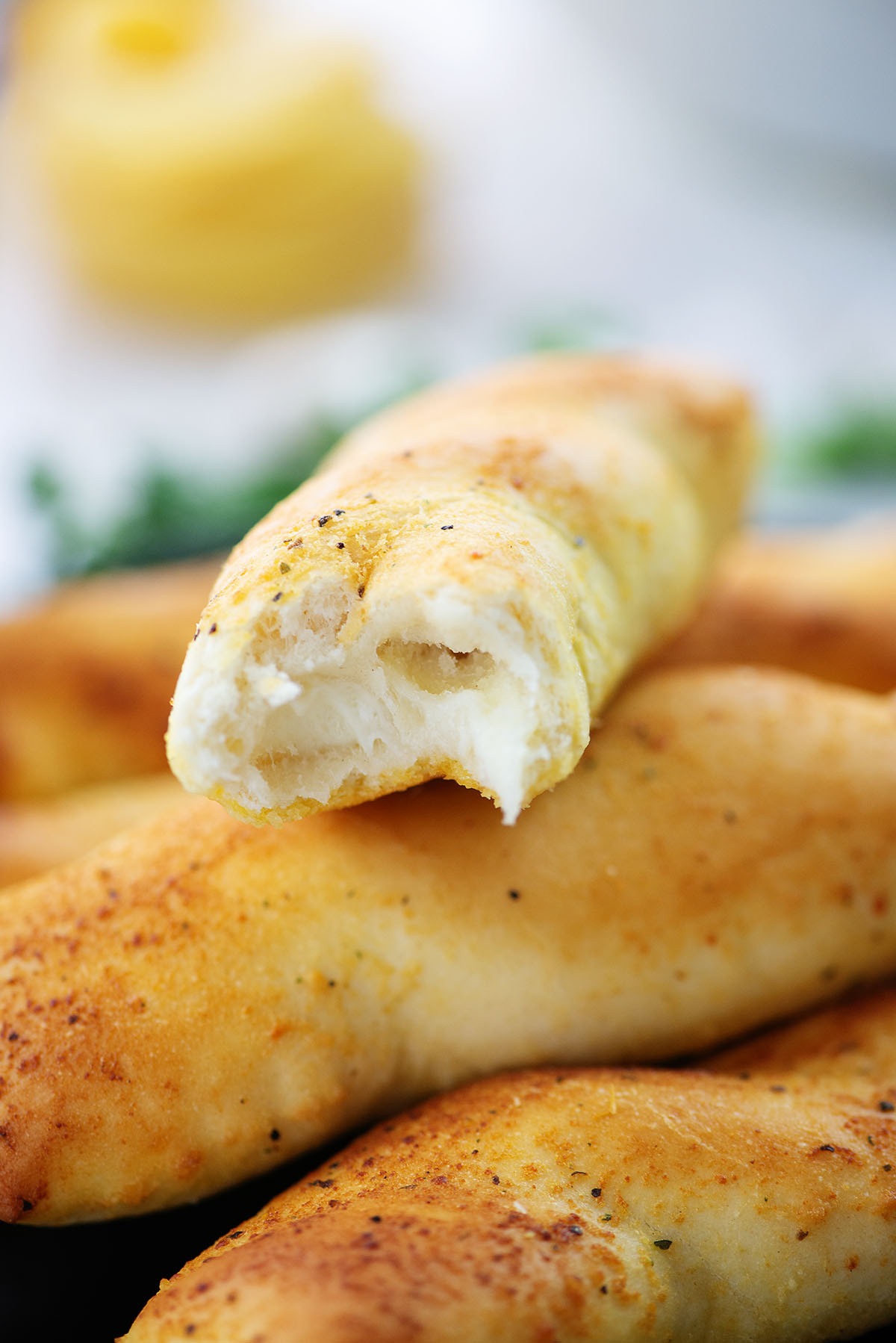 Close up of a breadstick with a bite out of it on top of another breadstick.