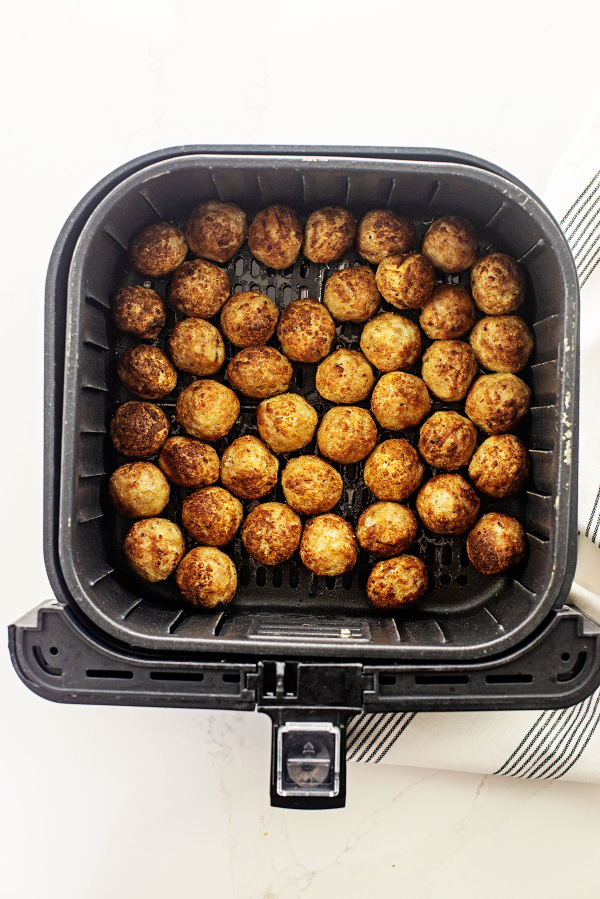 frozen meatballs in air fryer basket.