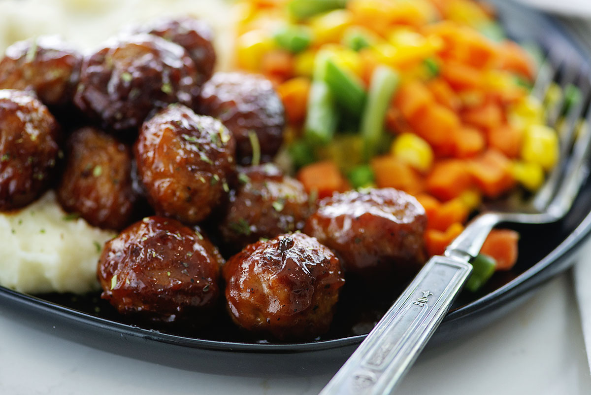 meatballs on black plate with vegetables.