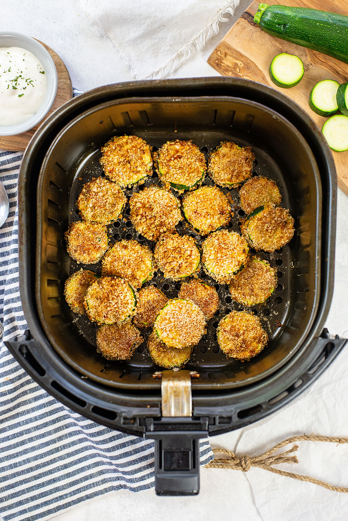 Overhead view of cooked air fried zucchini in an air fryer basket.