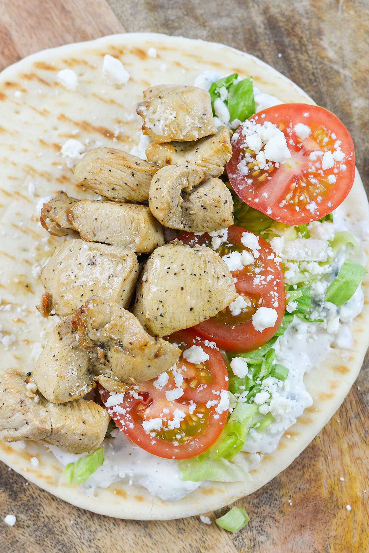 Open faced chicken pita filled tomatoes and feta cheese.