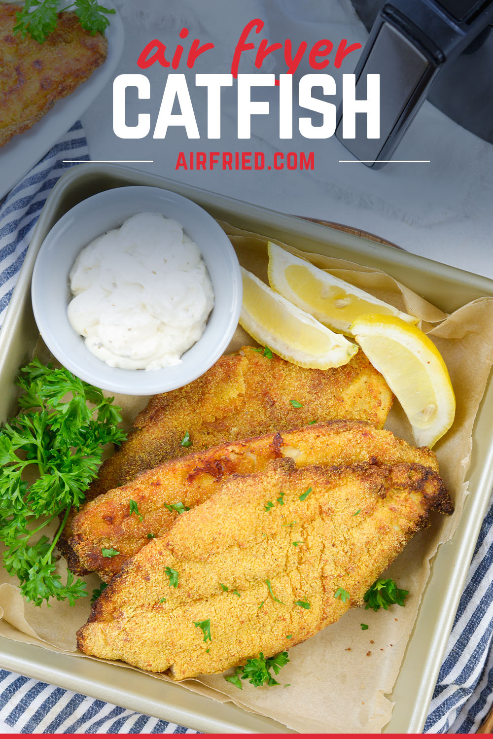 Catfish and lemon wedges on a square plate.