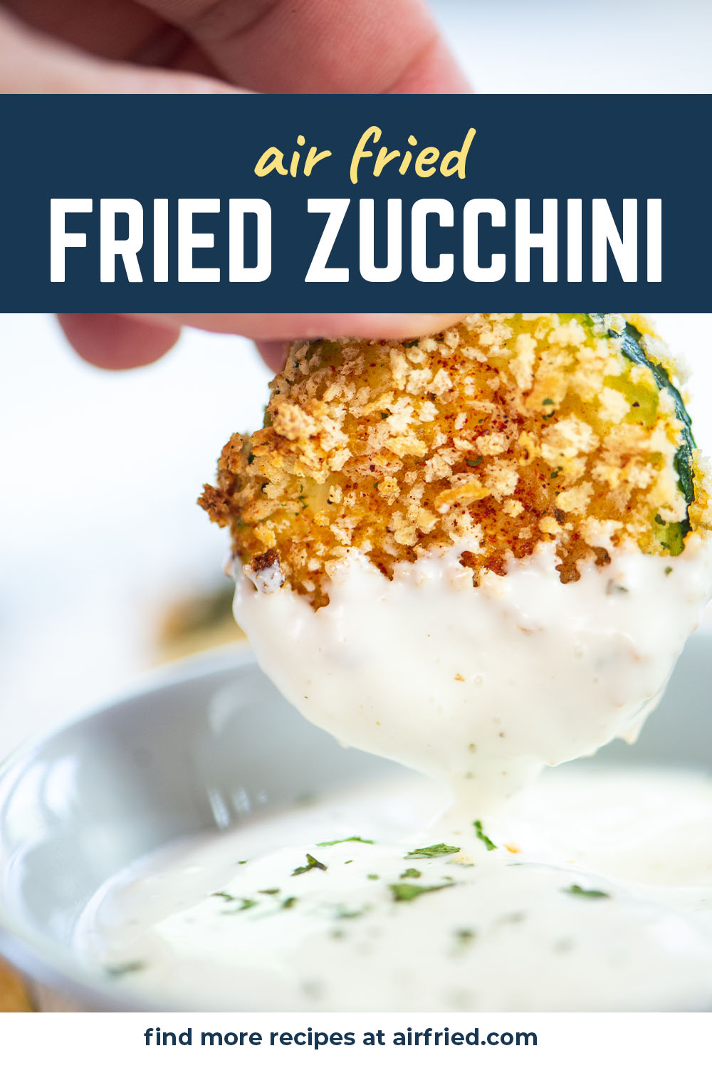 A person dipping fried zucchini into ranch dressing.