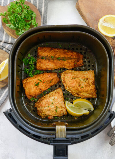 Overhead view of several salmon fillets in an air fryer cabinet.