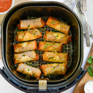 Overhead view of taco egg rolls in an air fryer basket.