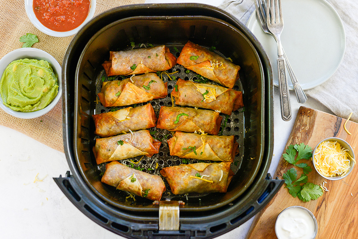 Overhead view of taco egg rolls in an air fryer basket.