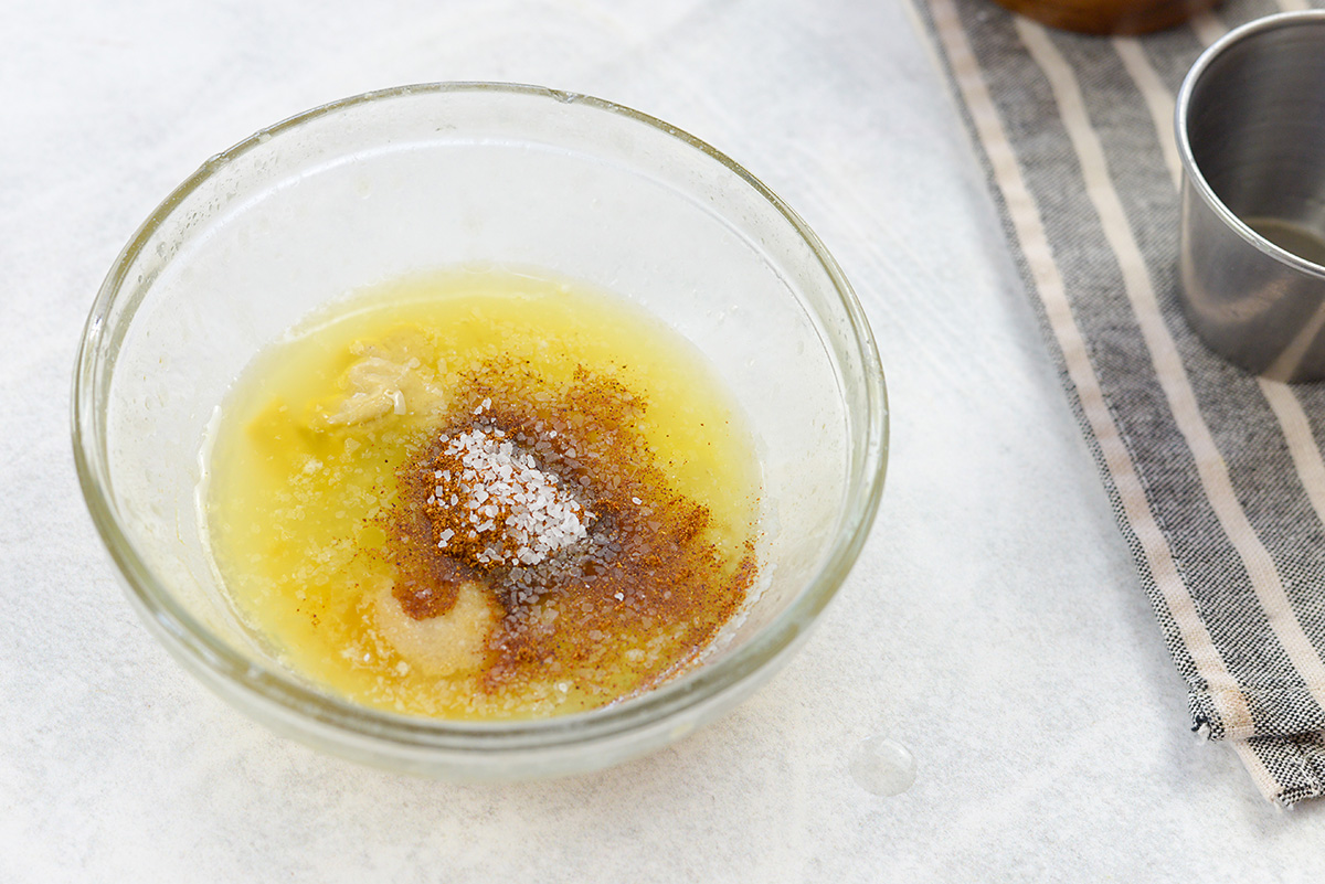 Glass bowl with melted butter and seasonings.