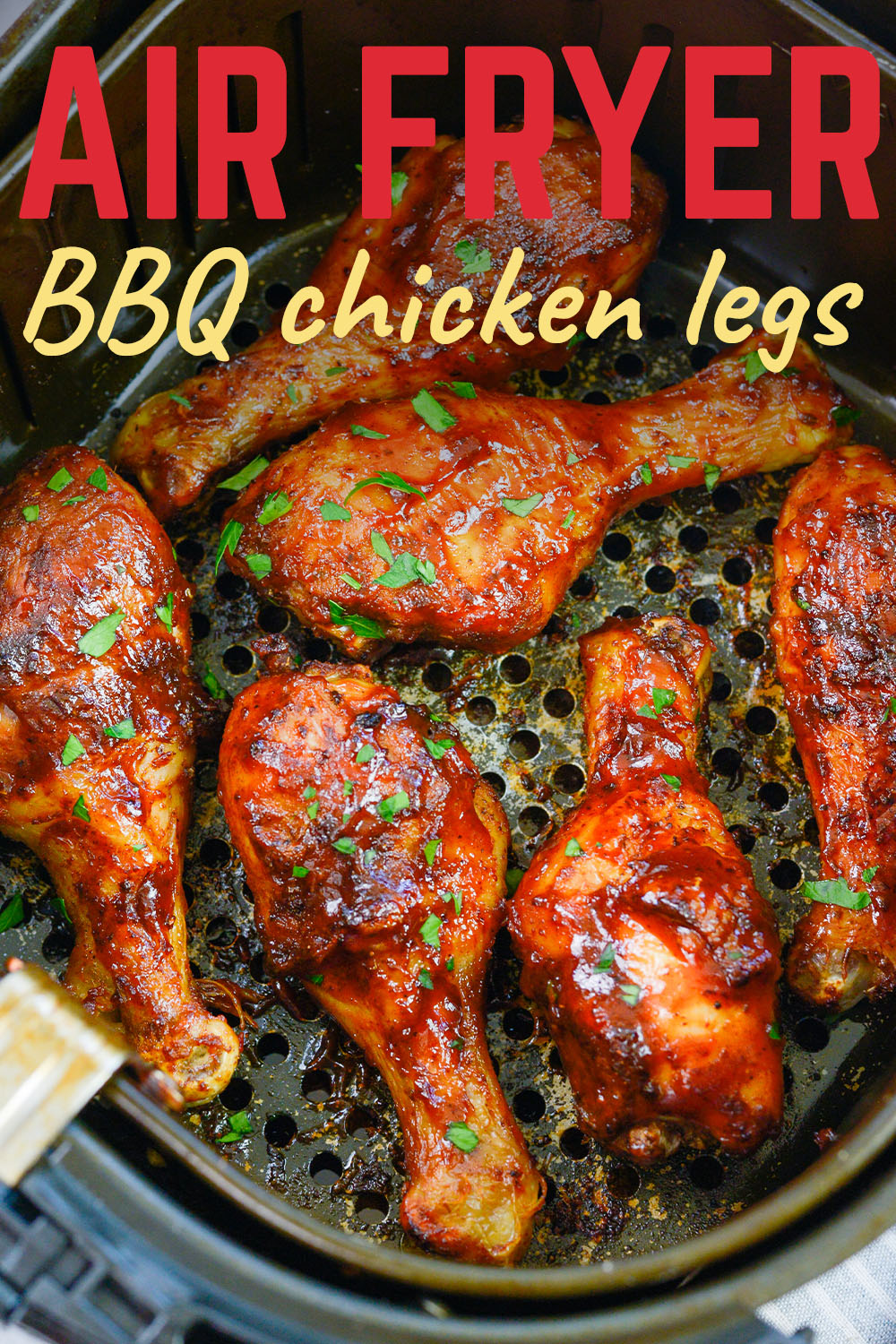 Several BBQ chicken legs in an air fryer basket.