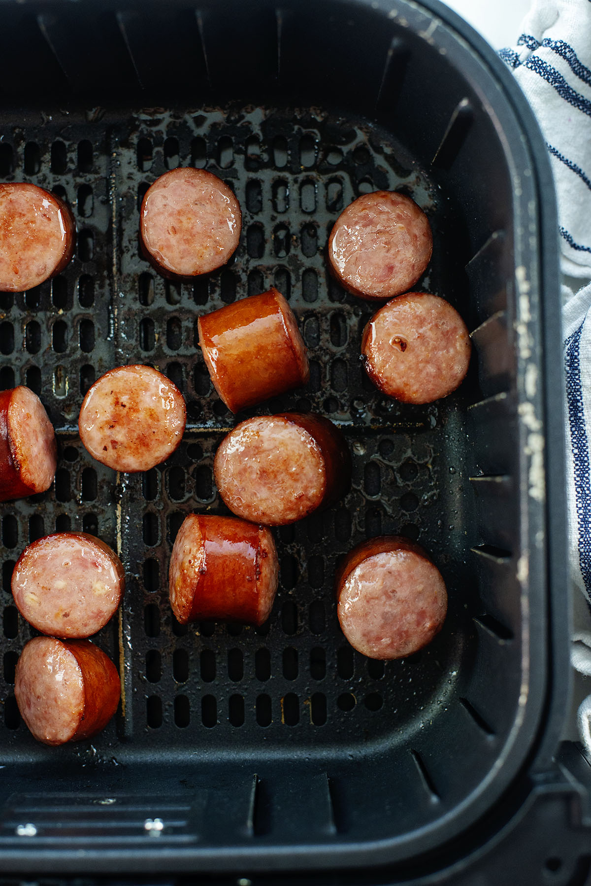 Smoked sausage chunks in an air fryer basket.