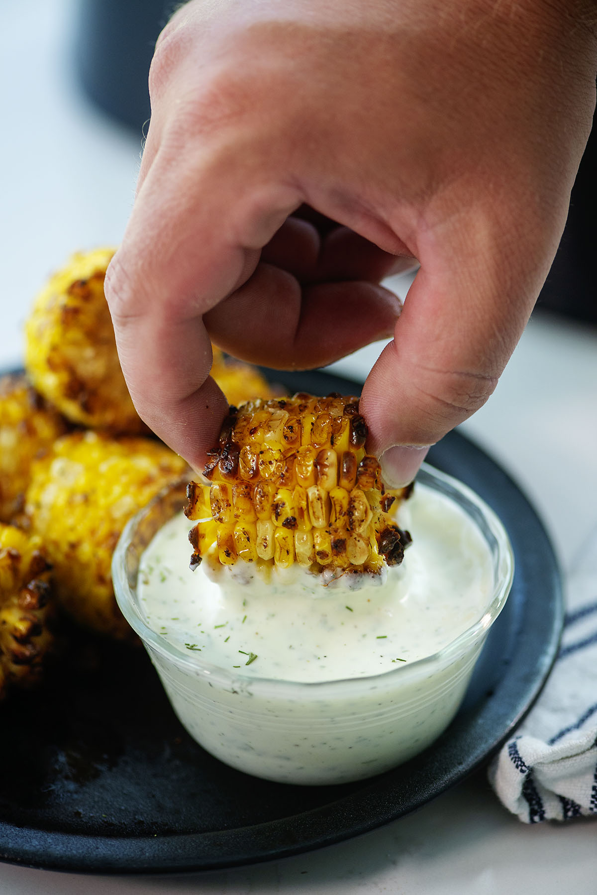 hand dipping corn into ranch dressing.