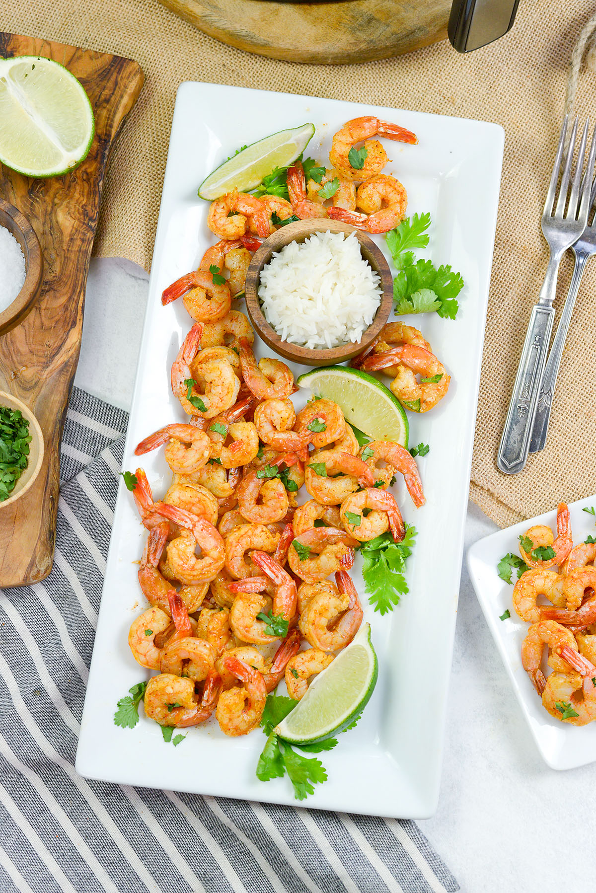 A serving platter with shrimp, lime, and rice on it.