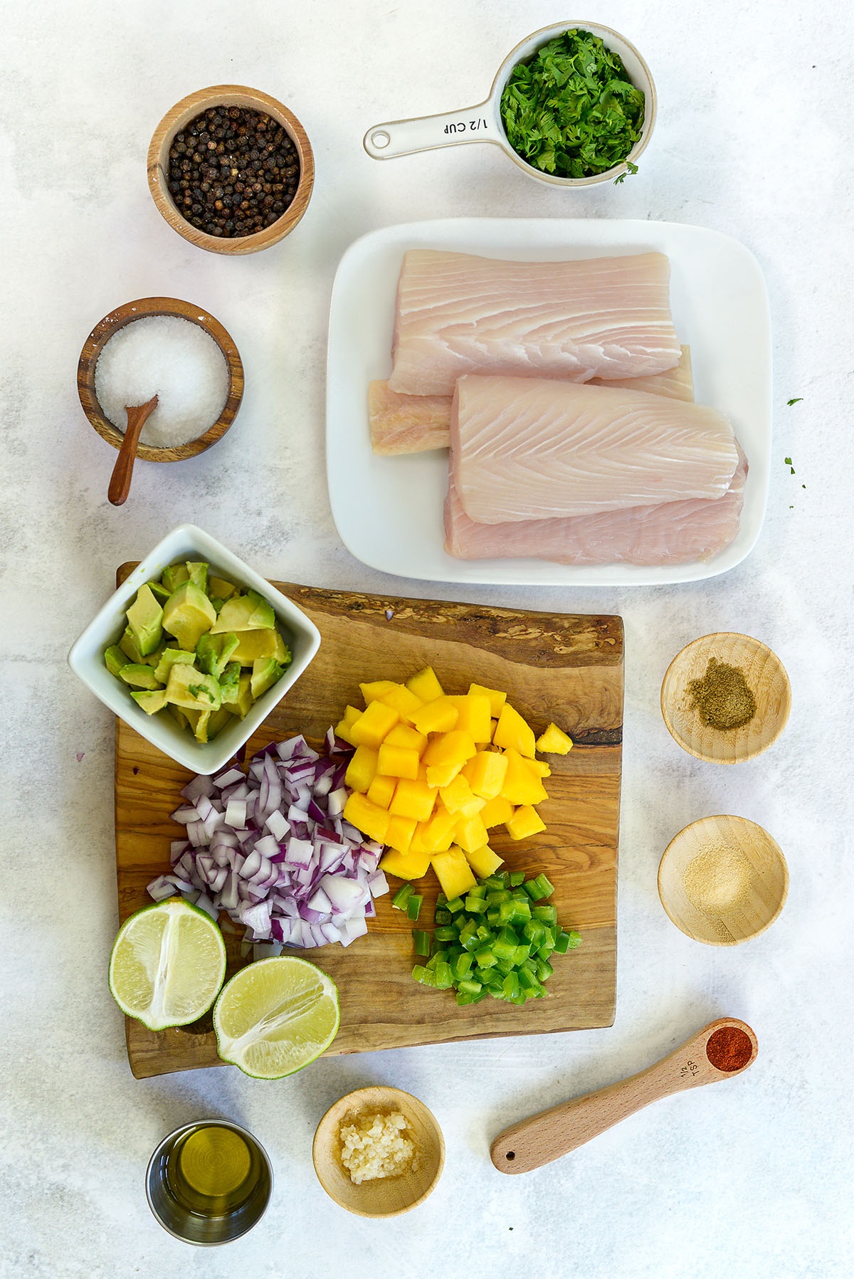 Mahi mahi and mango salsa ingredients spread out on a countertop.
