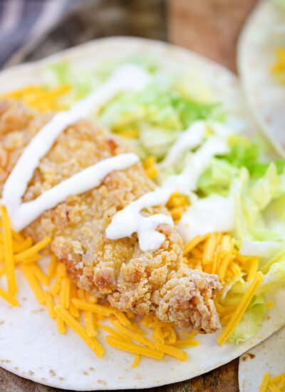 Close up of a chicken strip in a tortilla shell.