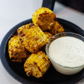 cajun fried corn on black plate with ranch dressing.