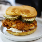 Close up of a chicken sandwich on a white plate.