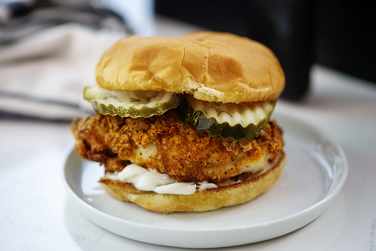 Close up of a chicken sandwich on a white plate.