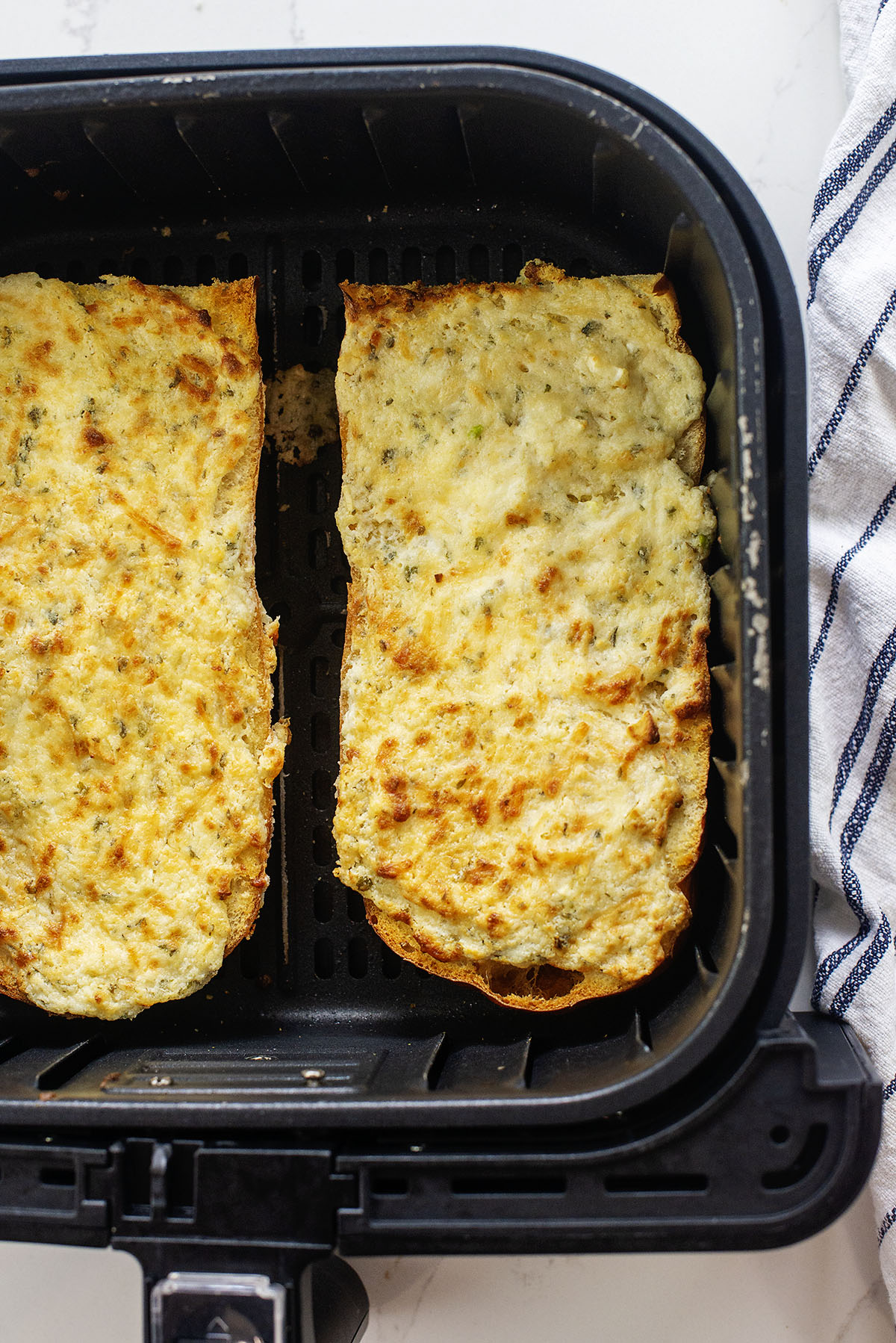 Two halves of garlic cheese bread in an air fryer basket.