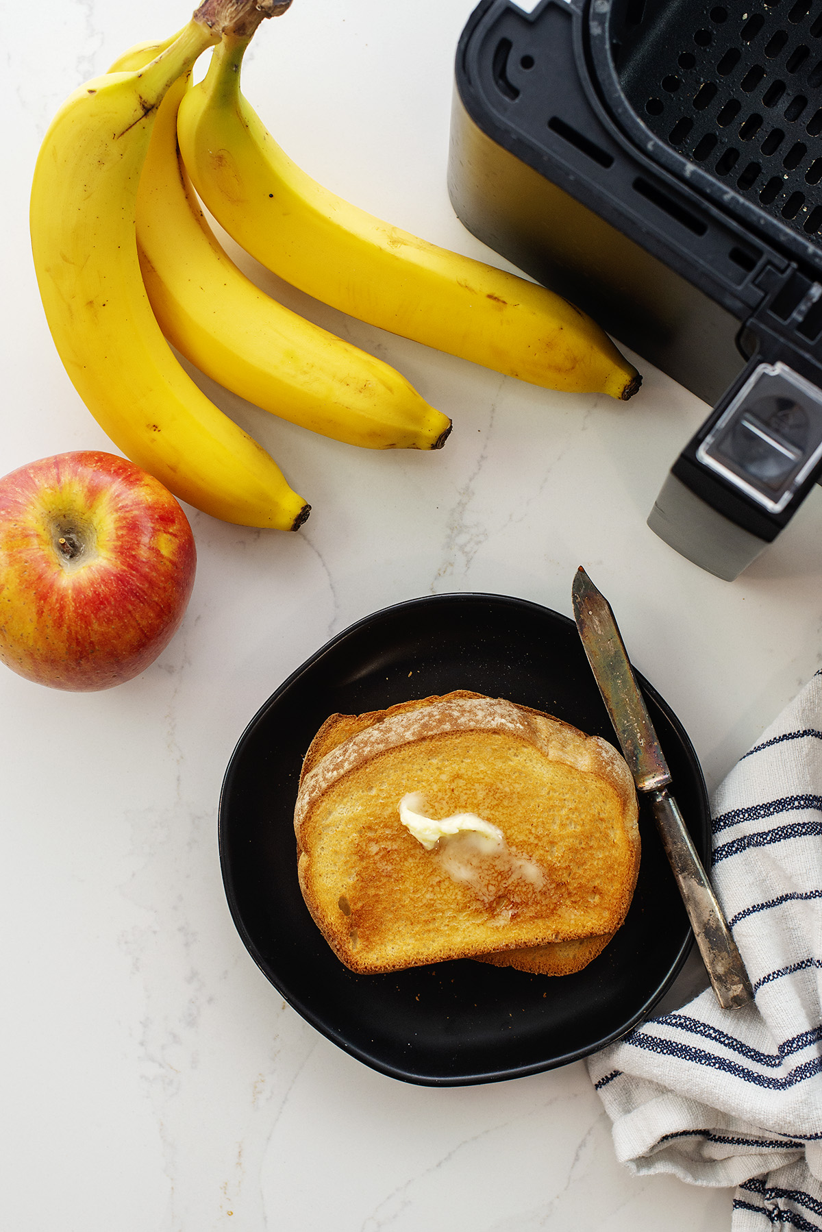 Toast next to bananas and an air fryer basket.