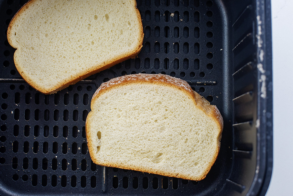 Two pieces of bread in an air fryer bsaket.