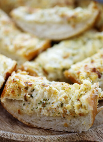 Close up of a single piece of garlic cheese bread.