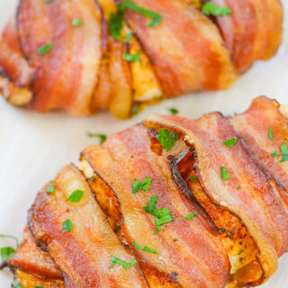 Two pieces of bacon wrapped chicken on a white plate.