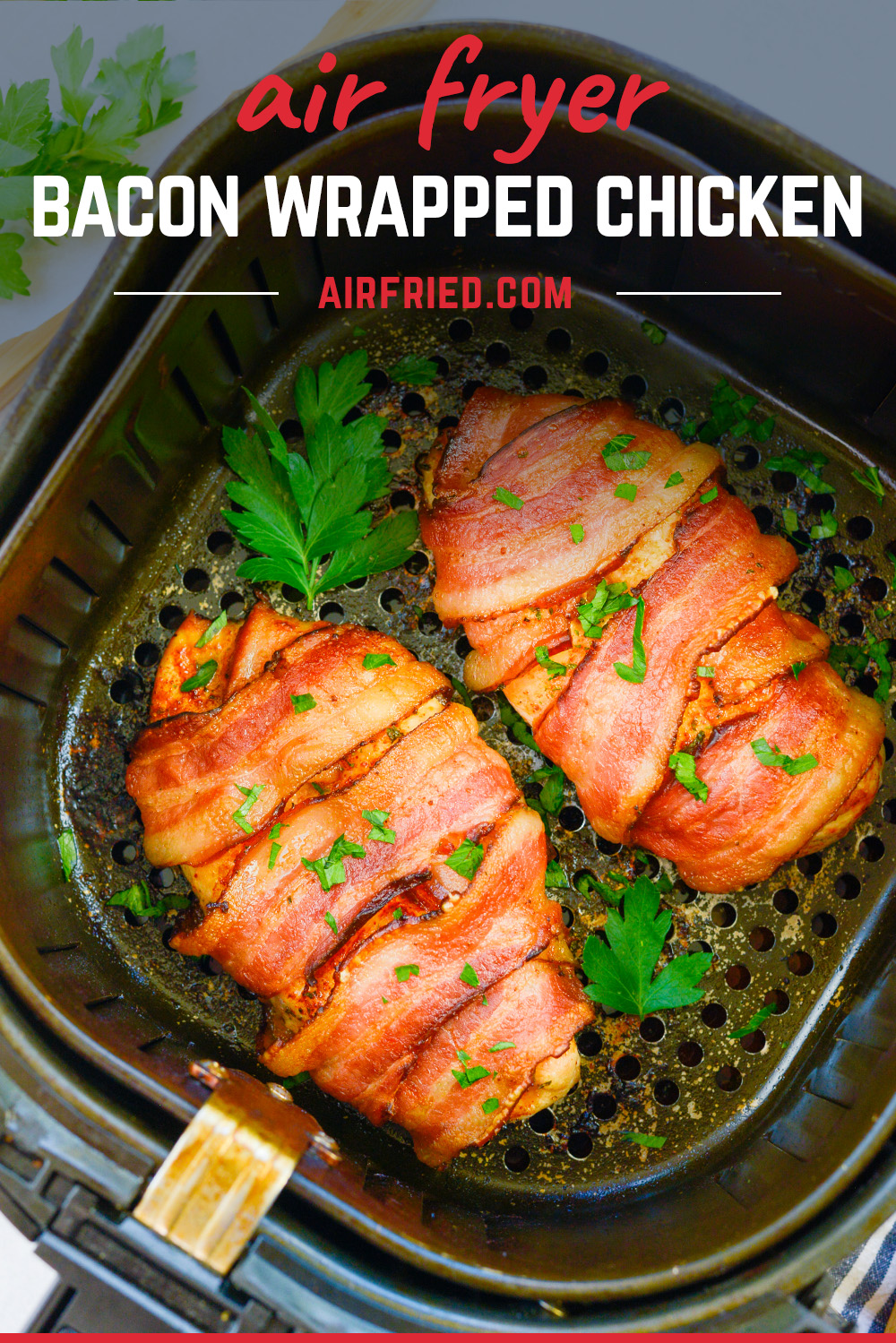 Two bacon wrapped chicken breasts garnished in an air fryer basket.
