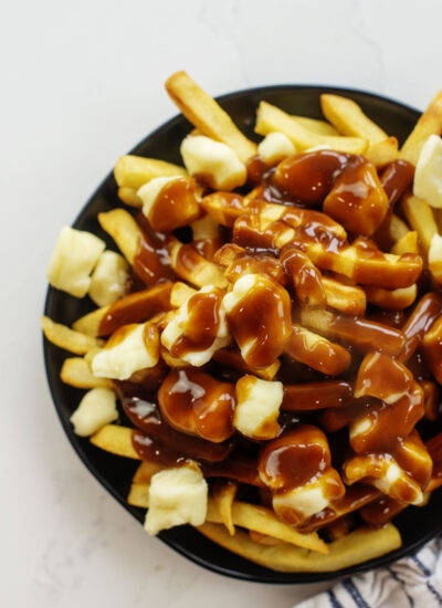 Overhead view of poutine on a small black plate.
