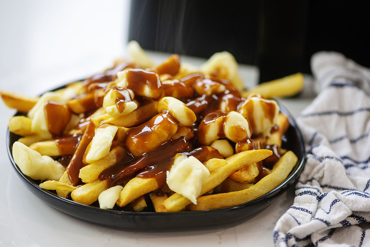 Poutine on a small black plate.