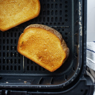 Two slices of toast in an air fryer basket.