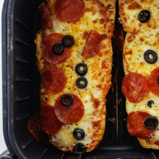 Overhead view of cooked French bread pizza in an air fryer basket.