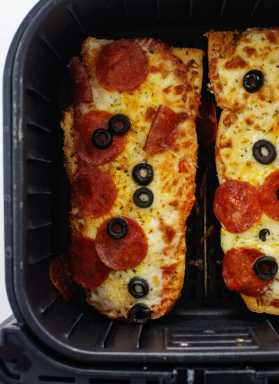 Overhead view of cooked French bread pizza in an air fryer basket.